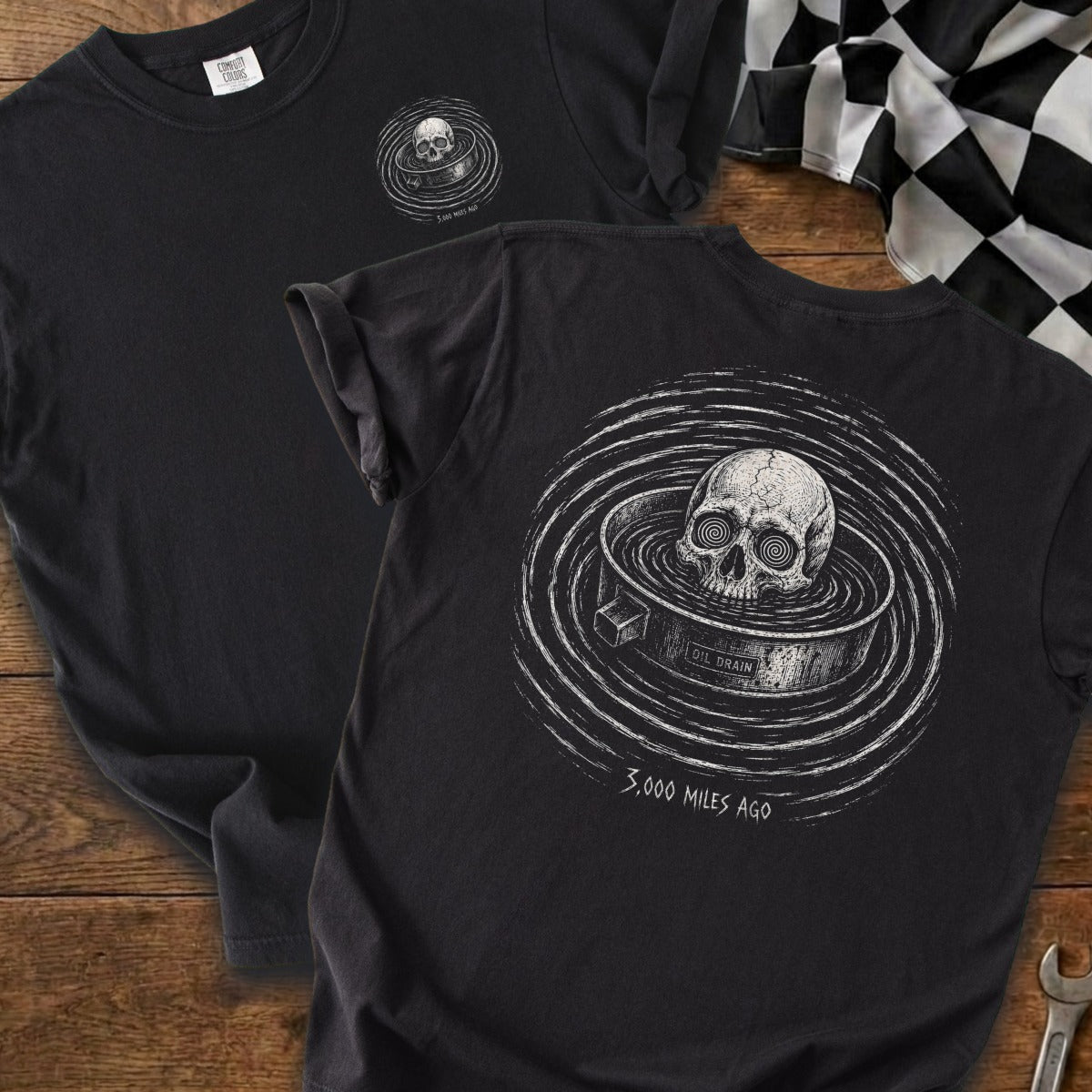 Black t-shirt with a skull in an oil drain and text "3,000 MILES AGO".