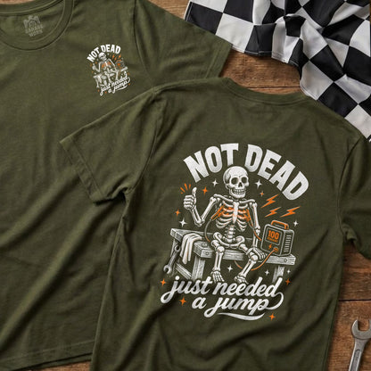 Green t-shirt with skeleton "Not Dead, Just Needed a Jump" graphic.