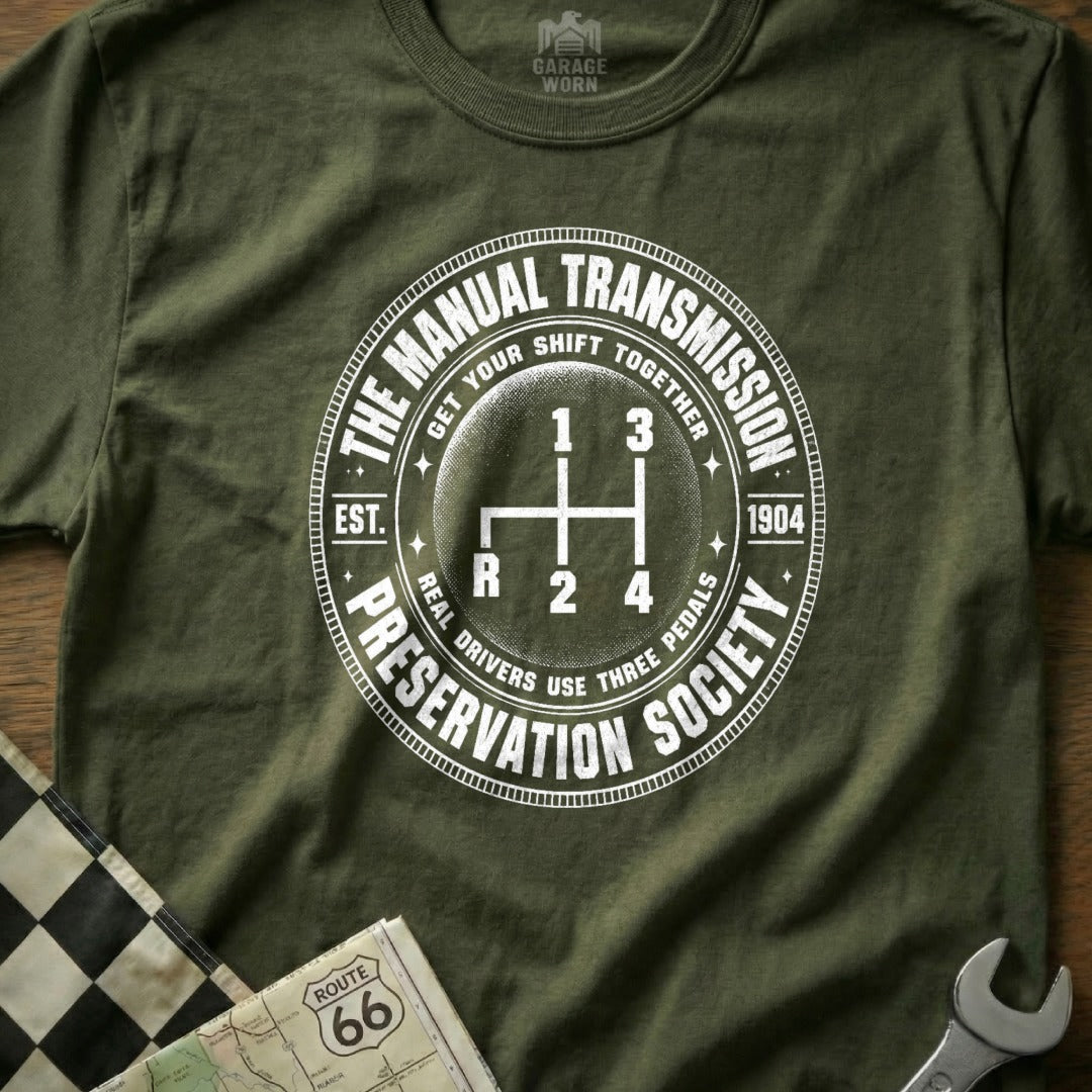 Green t-shirt with circular graphic for "The Manual Transmission Preservation Society" and gear shift.
