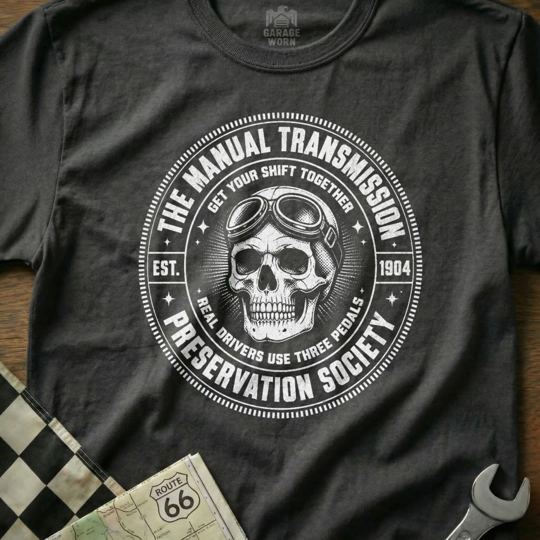 Dark grey t-shirt with skull, goggles, and "The Manual Transmission Preservation Society" text.
