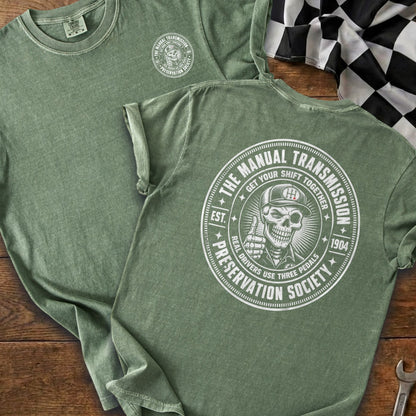 Green t-shirt with a circular graphic of a skeleton giving a thumbs-up.