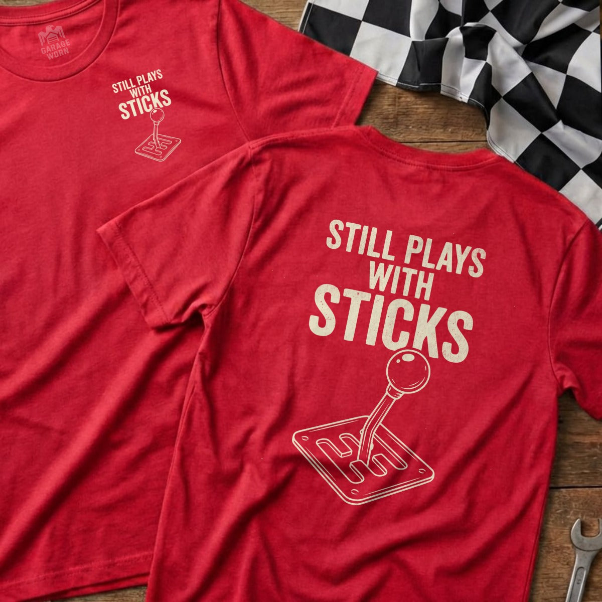 Two red t-shirts featuring "Still Plays With Sticks" and a manual gear shifter graphic.