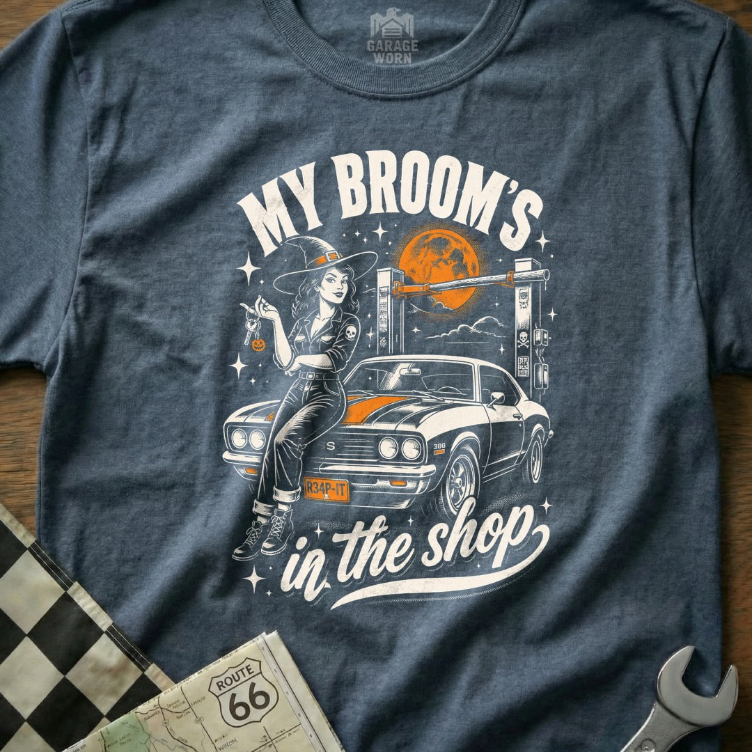 Witch with car and keys on lift, "My Broom's in the shop" text.