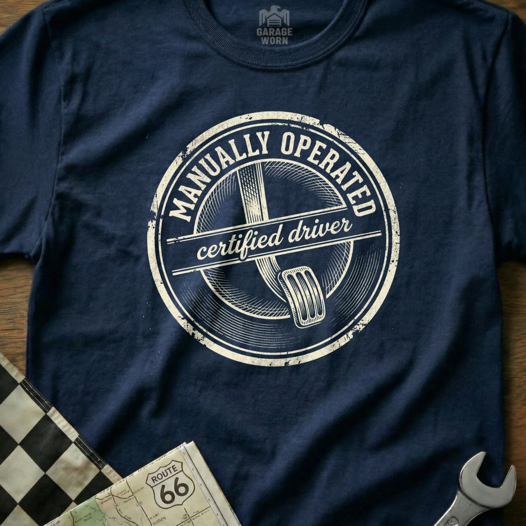 Navy t-shirt with "Manually Operated Certified Driver" in a circular distressed graphic.