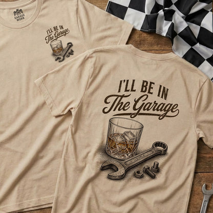 T-shirt with "I'll be in The Garage" text and whiskey glass, wrench, and bolts illustration.