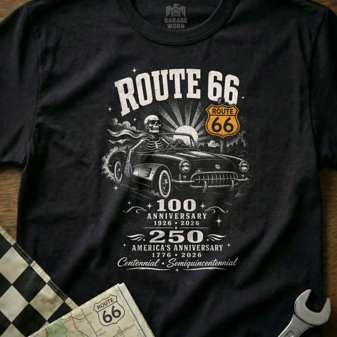 Black t-shirt graphic: Skeleton driving a vintage car, Route 66 signs, anniversary dates.