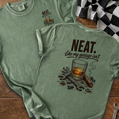 Green t-shirt with "NEAT. like my garage isn't" text and whiskey, cigar, and tools graphic.