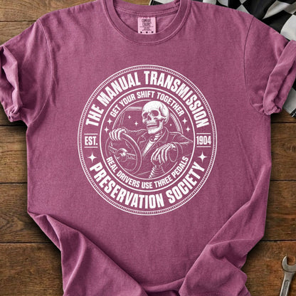 Skeleton driving a manual transmission car, "The Manual Transmission Preservation Society" text.