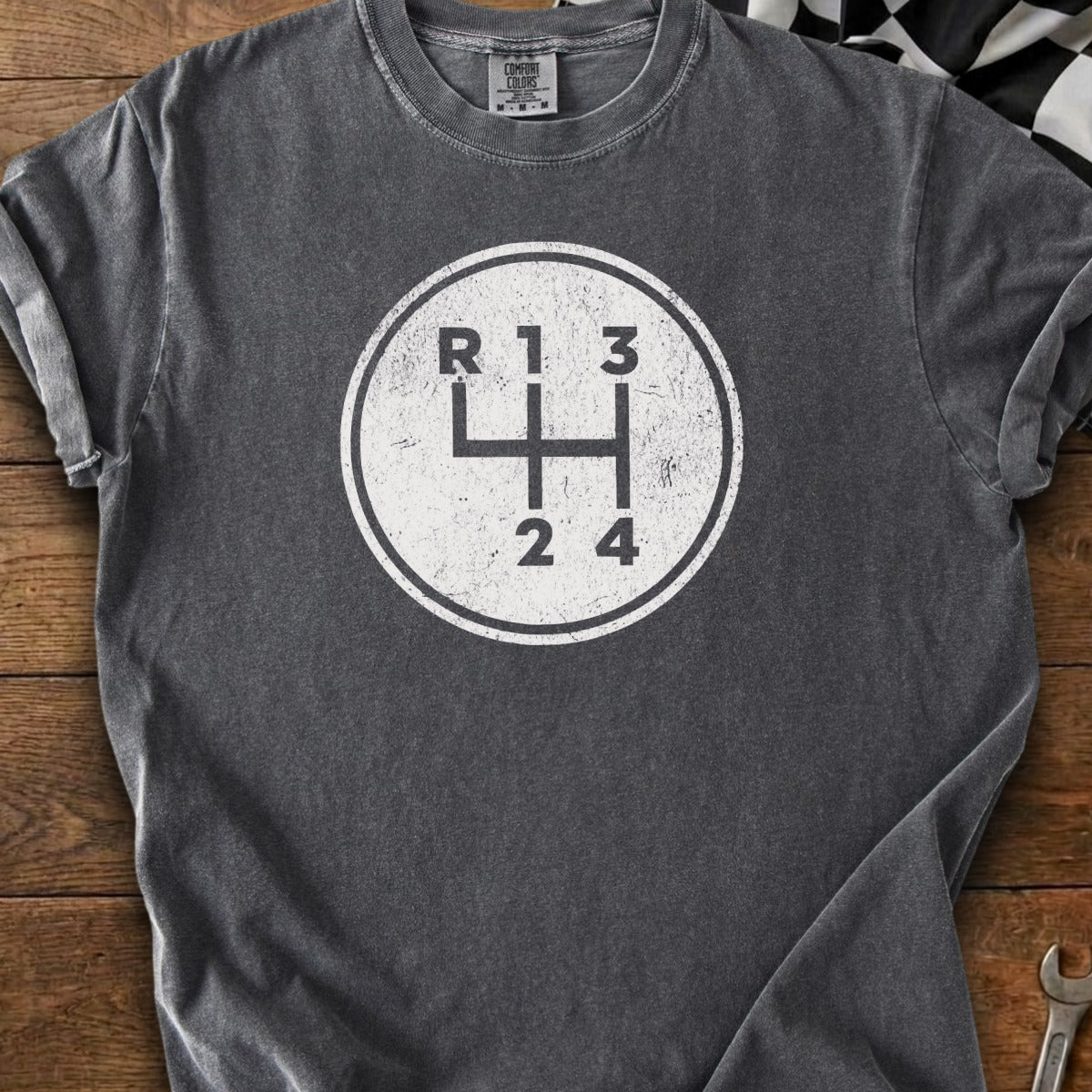 Dark grey t-shirt with a distressed white circle graphic of a manual transmission shift pattern.