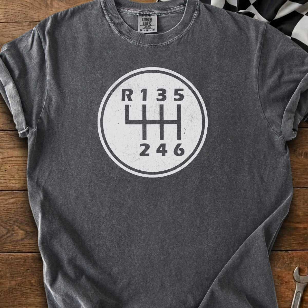 Dark gray t-shirt with a white manual transmission shift pattern graphic.