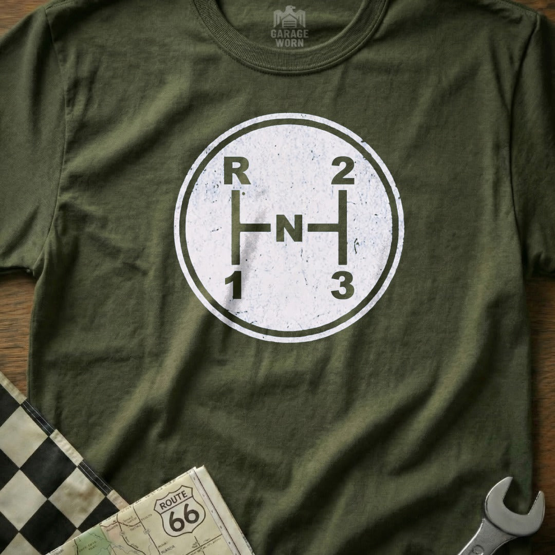 Green shirt with distressed vintage manual transmission shift pattern graphic.