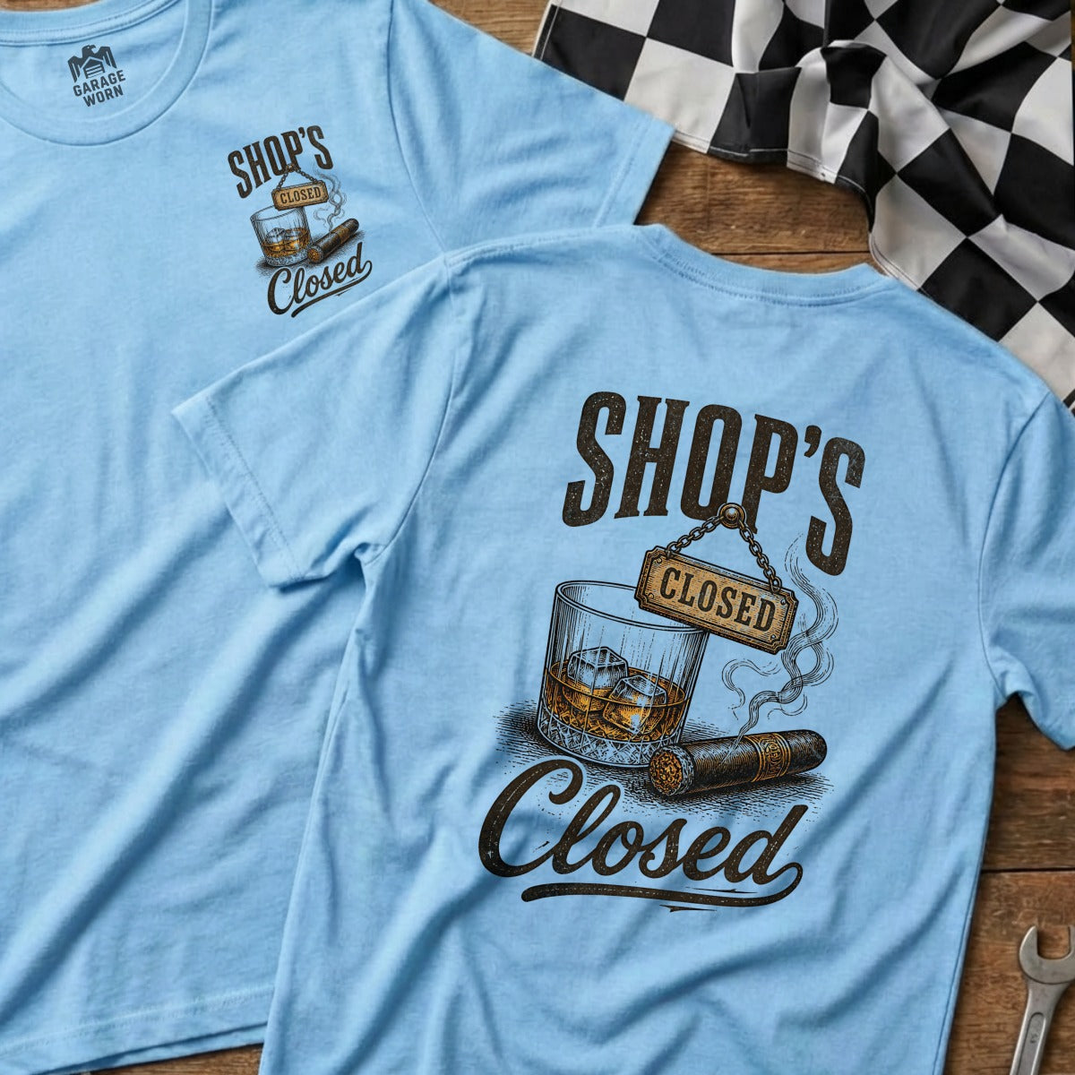 Light blue t-shirt with "SHOP'S CLOSED" text, a glass of whiskey, and a cigar.