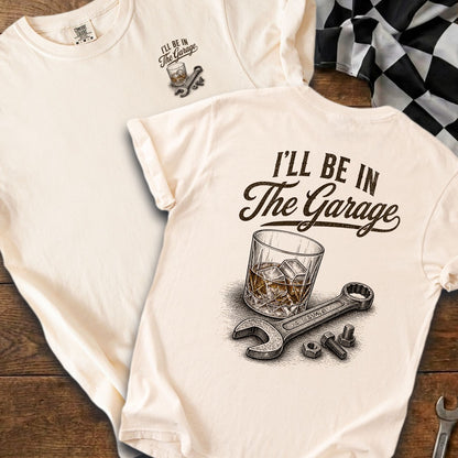 Cream shirt with "I'll Be In The Garage" text, whiskey glass, wrench, and bolts.
