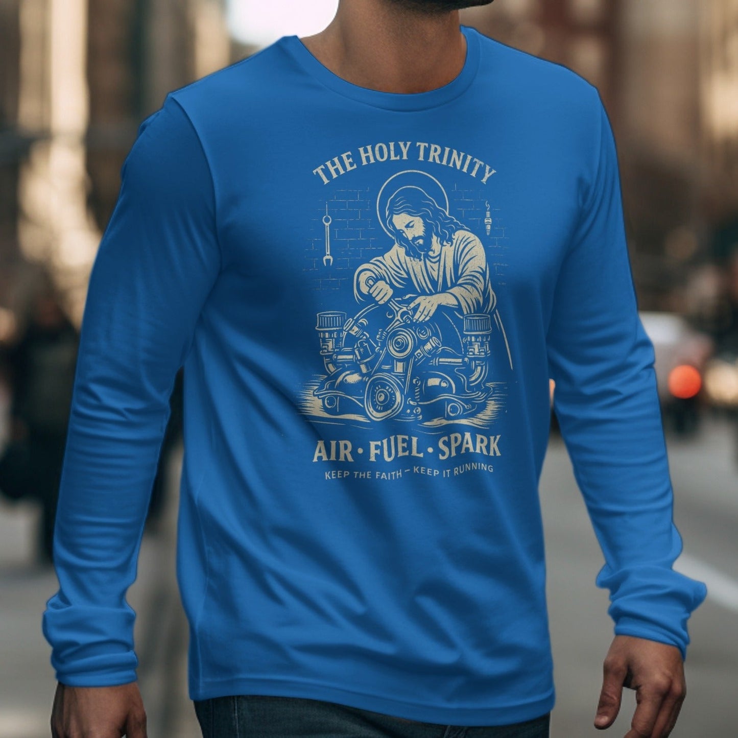 Blue long-sleeve shirt with graphic of Jesus working on an engine, "The Holy Trinity" and "Air Fuel Spark" text.