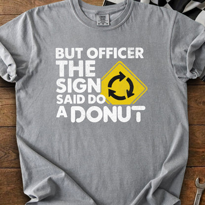 Gray t-shirt with white text: "BUT OFFICER THE SIGN SAID DO A DONUT" and roundabout symbol.