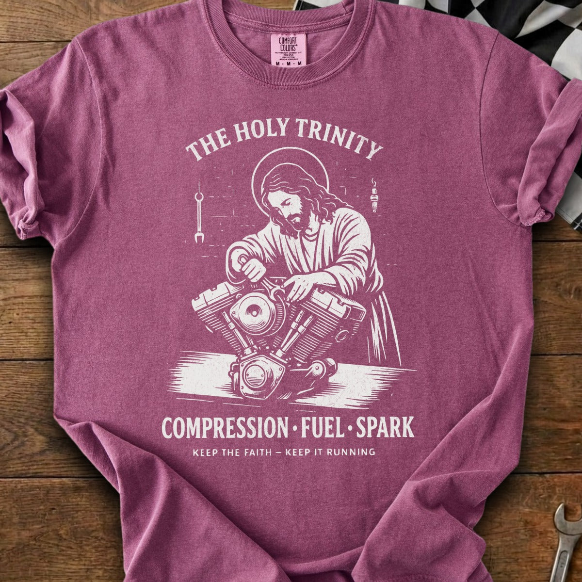 Jesus working on a motorcycle engine with text "The Holy Trinity" and "Compression Fuel Spark".