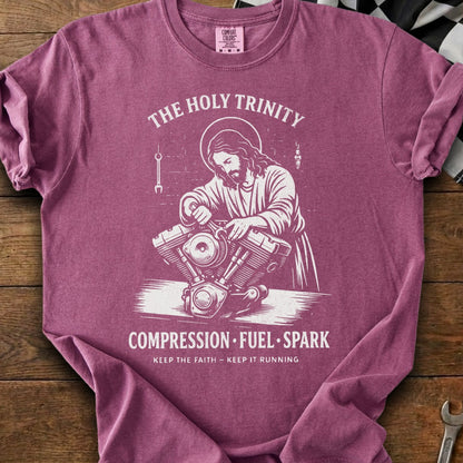 Jesus working on a motorcycle engine with text "The Holy Trinity" and "Compression Fuel Spark".