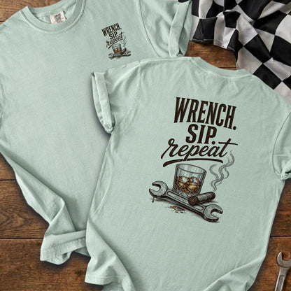 Light blue t-shirt with "Wrench. Sip. Repeat." and illustration of whiskey, cigar, and wrenches.