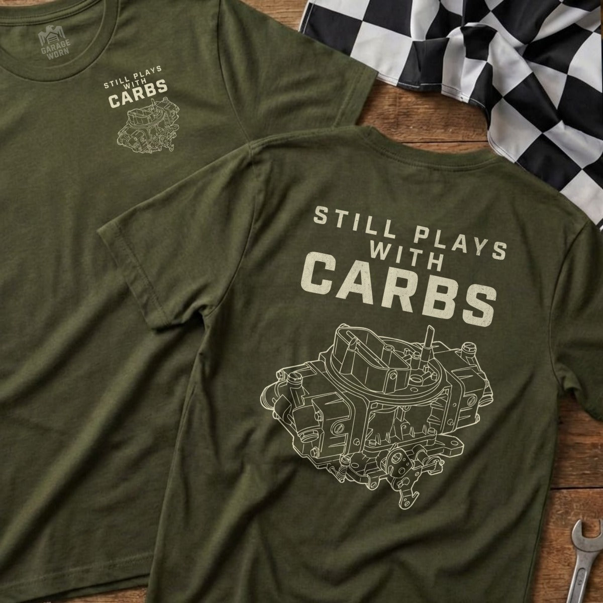 Olive green t-shirt with a graphic of a carburetor and the text "STILL PLAYS WITH CARBS".