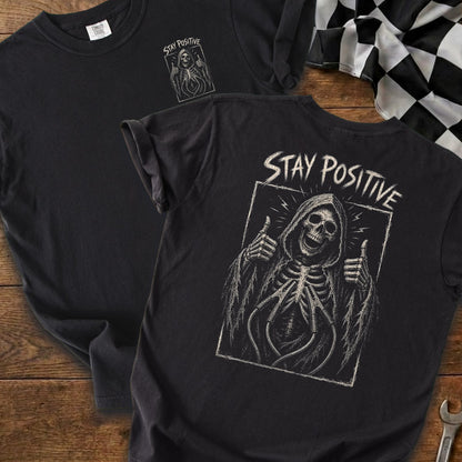 Black t-shirt with grim reaper graphic and "STAY POSITIVE" text.