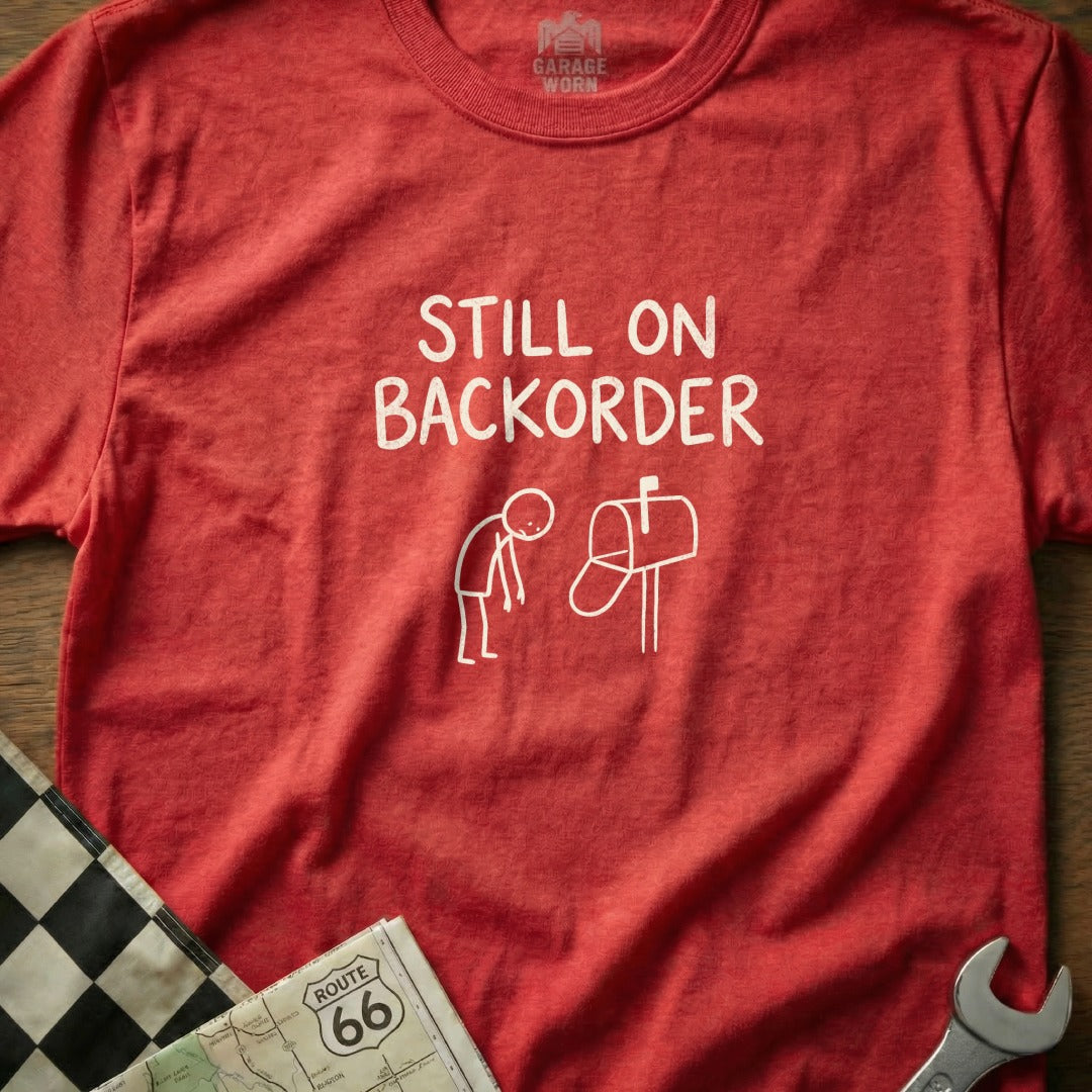 Red t-shirt with "Still on Backorder" text and stick figure at mailbox.
