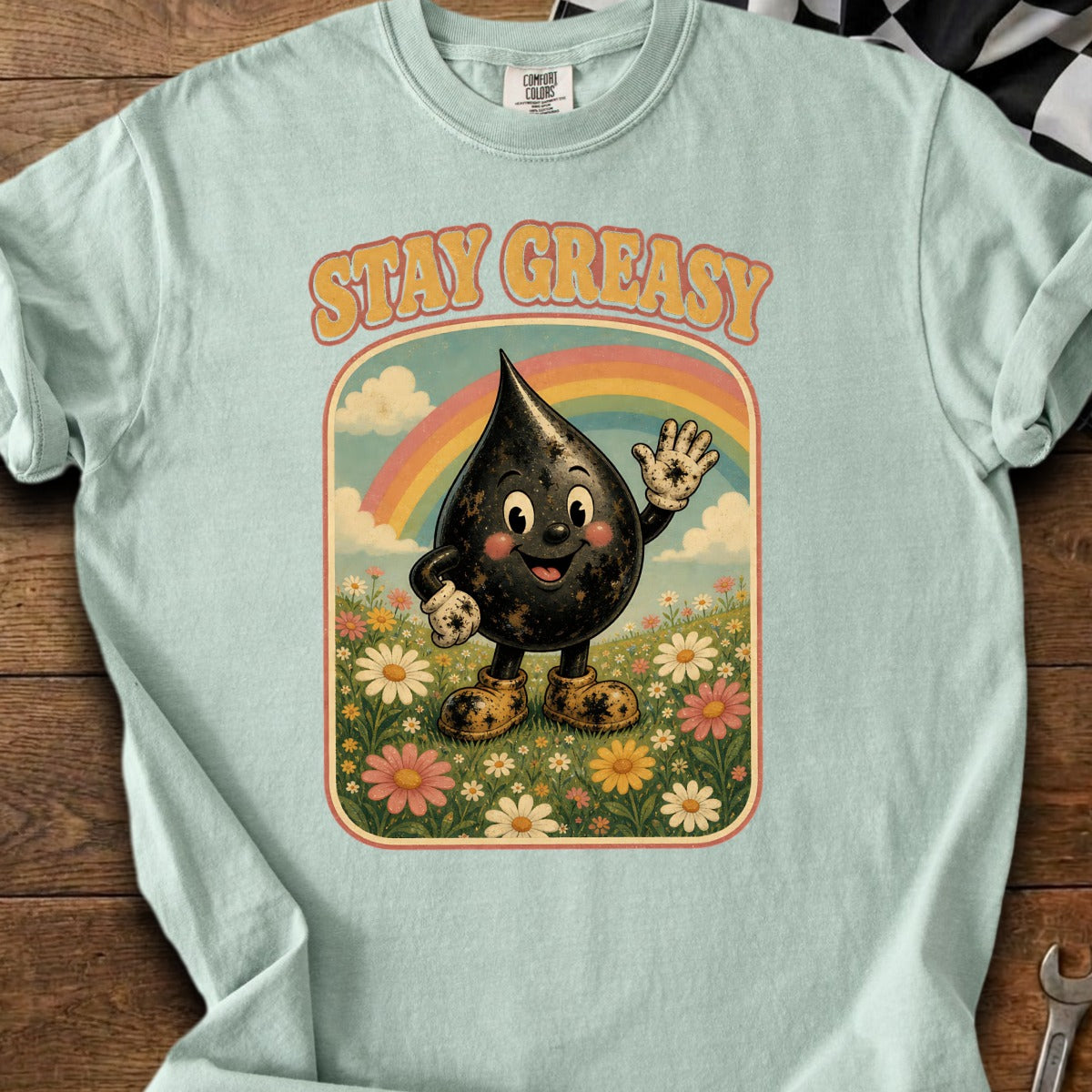 Light blue t-shirt with "STAY GREASY" and a waving cartoon oil drop character in a meadow.