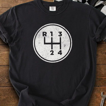 Black t-shirt with a distressed white circular graphic of a manual car gear shift pattern.