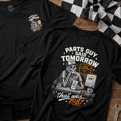Black t-shirt graphic with skeleton, calendar, and "Parts Guy Said Tomorrow, That Was 1987".