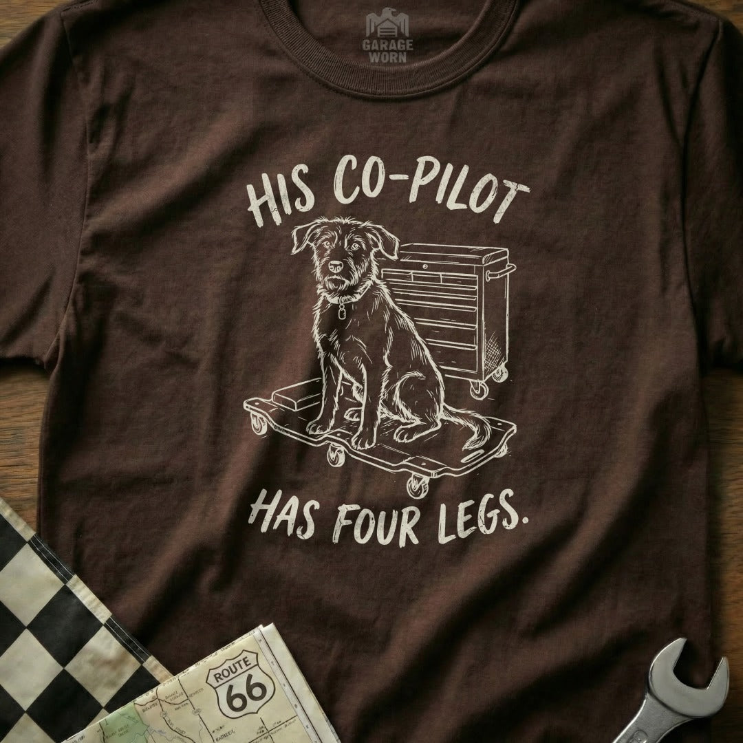Brown t-shirt with a sketch of a dog on a toolbox and the text "HIS CO-PILOT HAS FOUR LEGS."