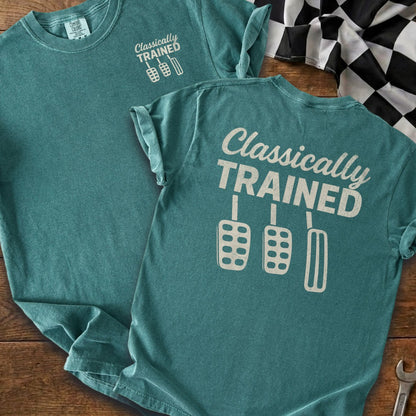 Teal t-shirt with "Classically TRAINED" text and three car pedals graphic.