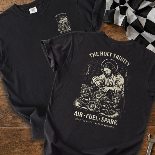Black t-shirt with "The Holy Trinity" and Jesus working on an engine.