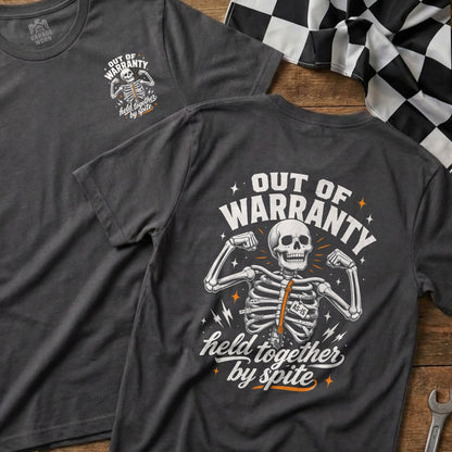Dark gray t-shirt with a graphic of a skeleton flexing muscles with "OUT OF WARRANTY held together by spite" text.