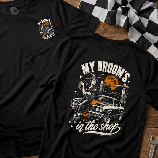 Black t-shirt with a witch on a car graphic and text "My Broom's in the Shop".
