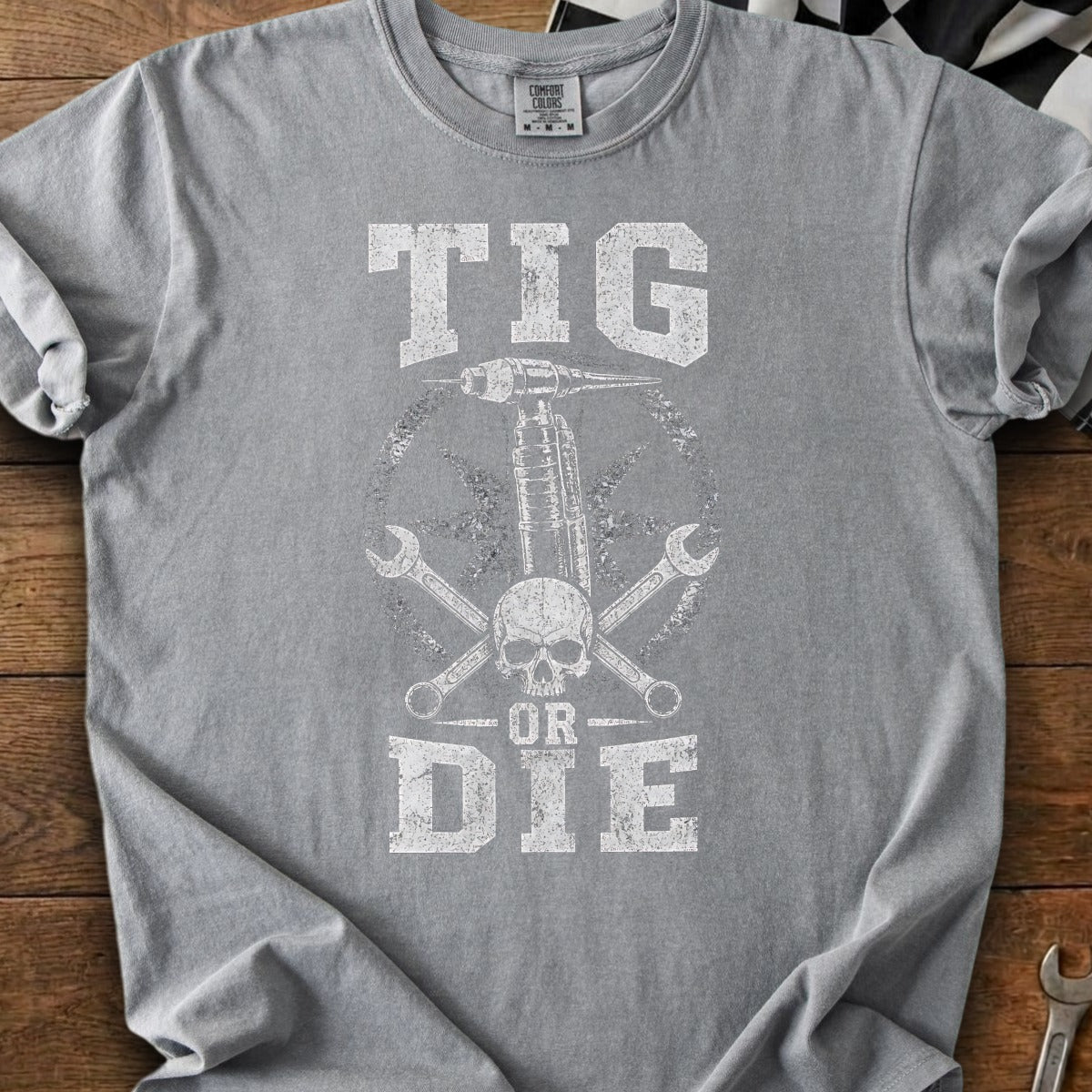 Grey t-shirt with distressed "TIG OR DIE" graphic and welding equipment.
