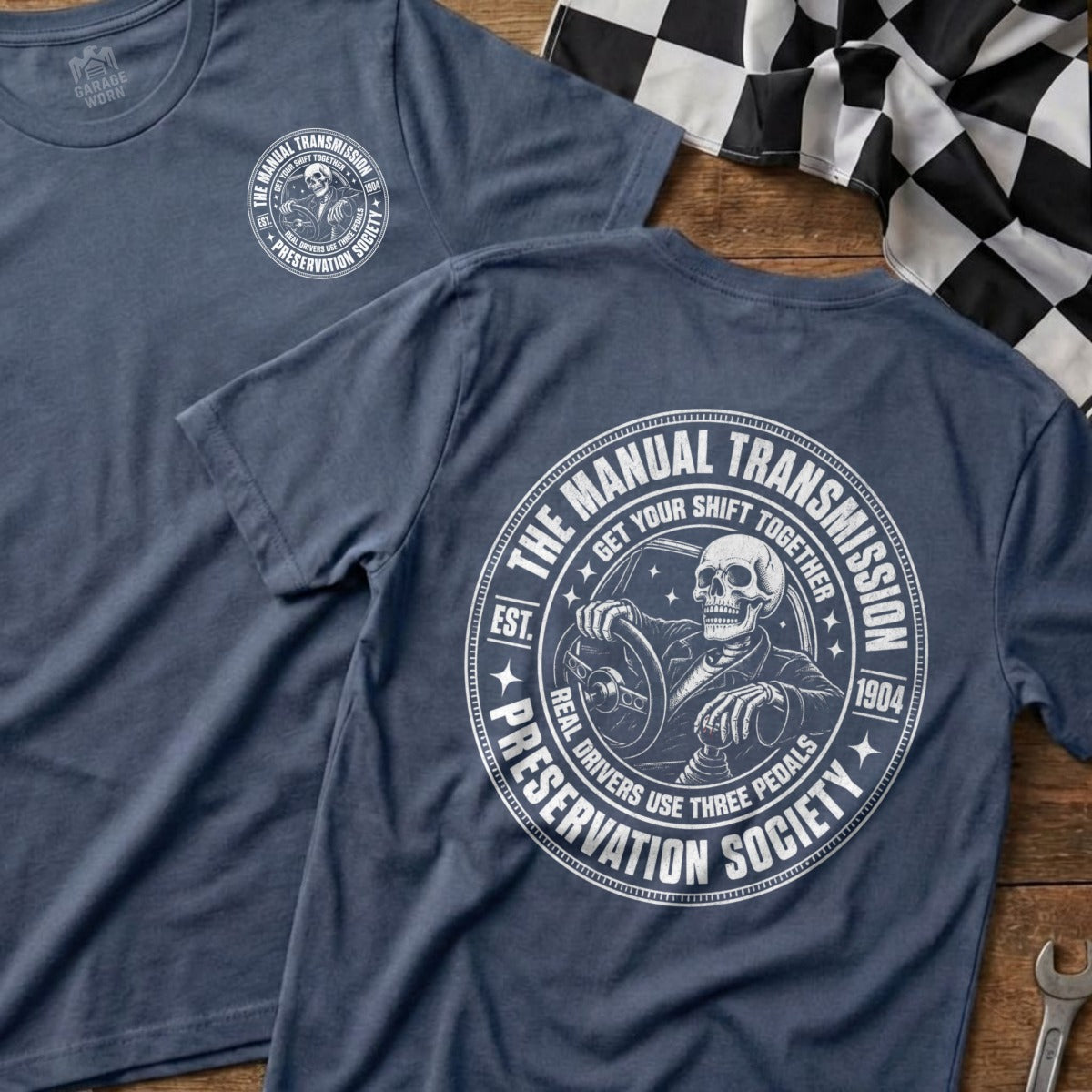 Gray t-shirt with skeleton driving graphic, text "Manual Transmission Preservation Society".