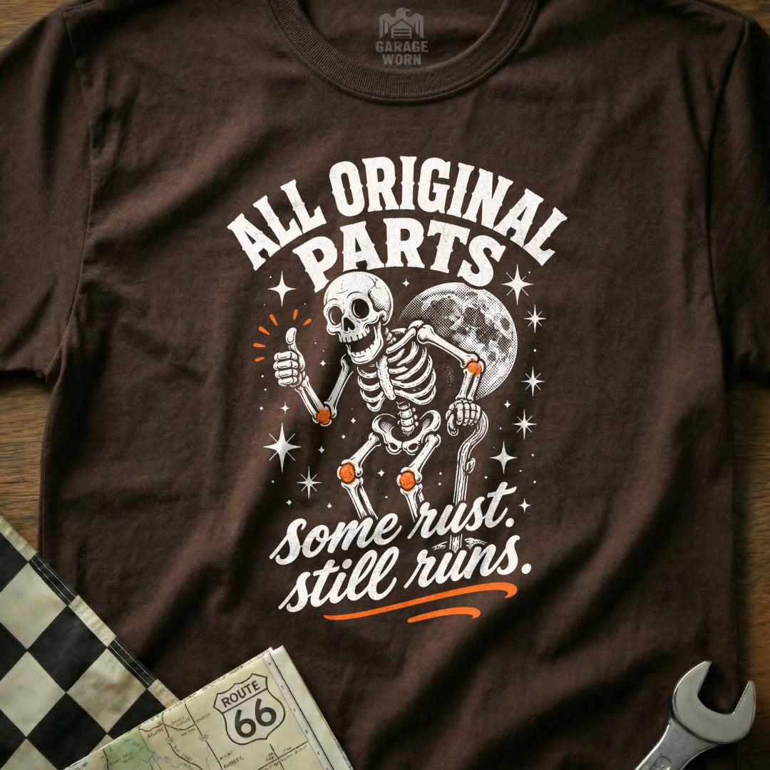 Brown t-shirt with skeleton, moon, and text "All Original Parts, Some Rust. Still Runs."
