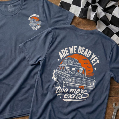 T-shirt with graphic of skeletons driving a car, text "ARE WE DEAD YET two more exits".
