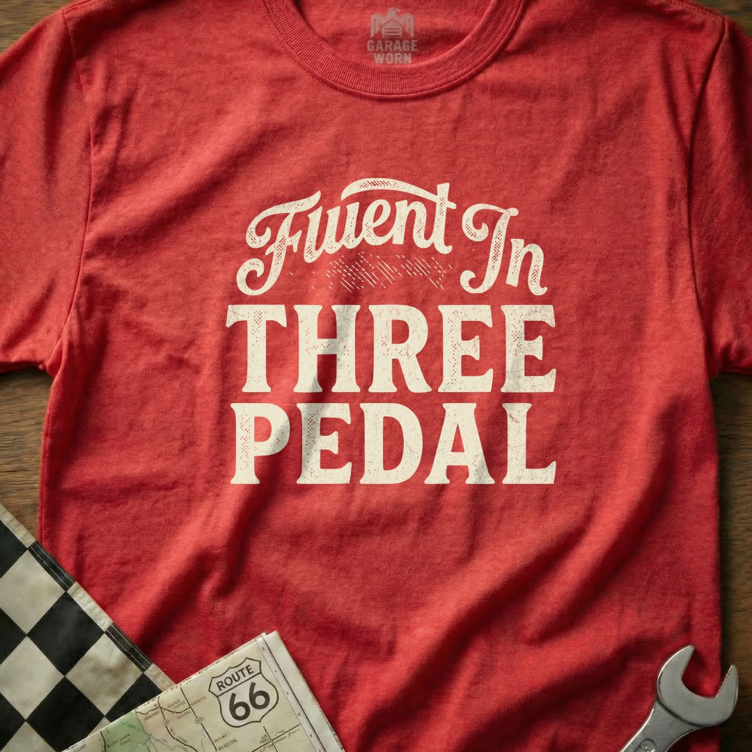 Red t-shirt with "Fluent In THREE PEDAL" text, checkered flag, and map.
