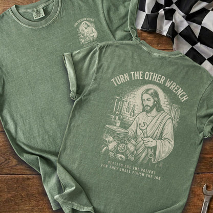 Green t-shirt with Jesus holding a wrench and engine. Text reads "Turn the other wrench".