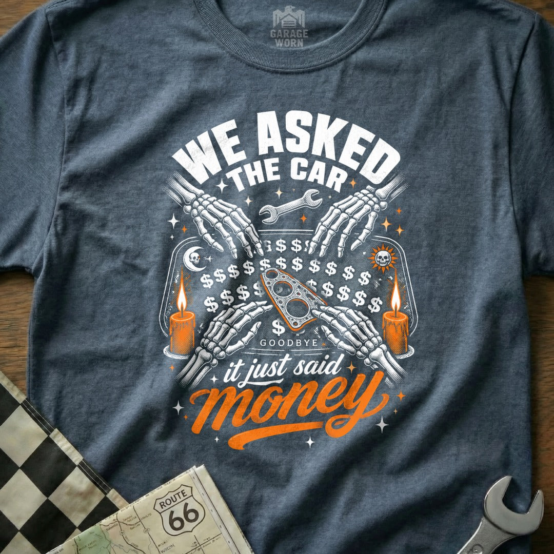 T-shirt graphic with skeleton hands, candles, and text: "WE ASKED THE CAR... it just said money."
