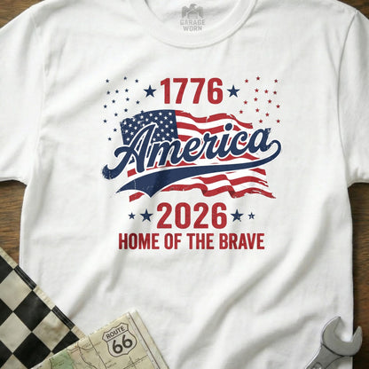 White t-shirt with "1776 America 2026 Home of the Brave" and US flag design.