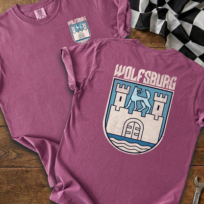 Two purple t-shirts featuring a blue and white Wolfsburg crest with a wolf or dog.