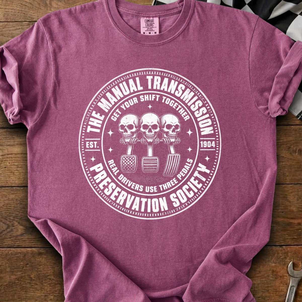 Shirt with manual transmission society graphic featuring skulls and pedals.