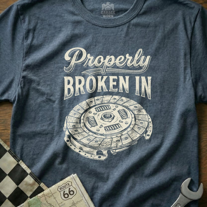 T-shirt with "Properly Broken In" text and a clutch illustration.