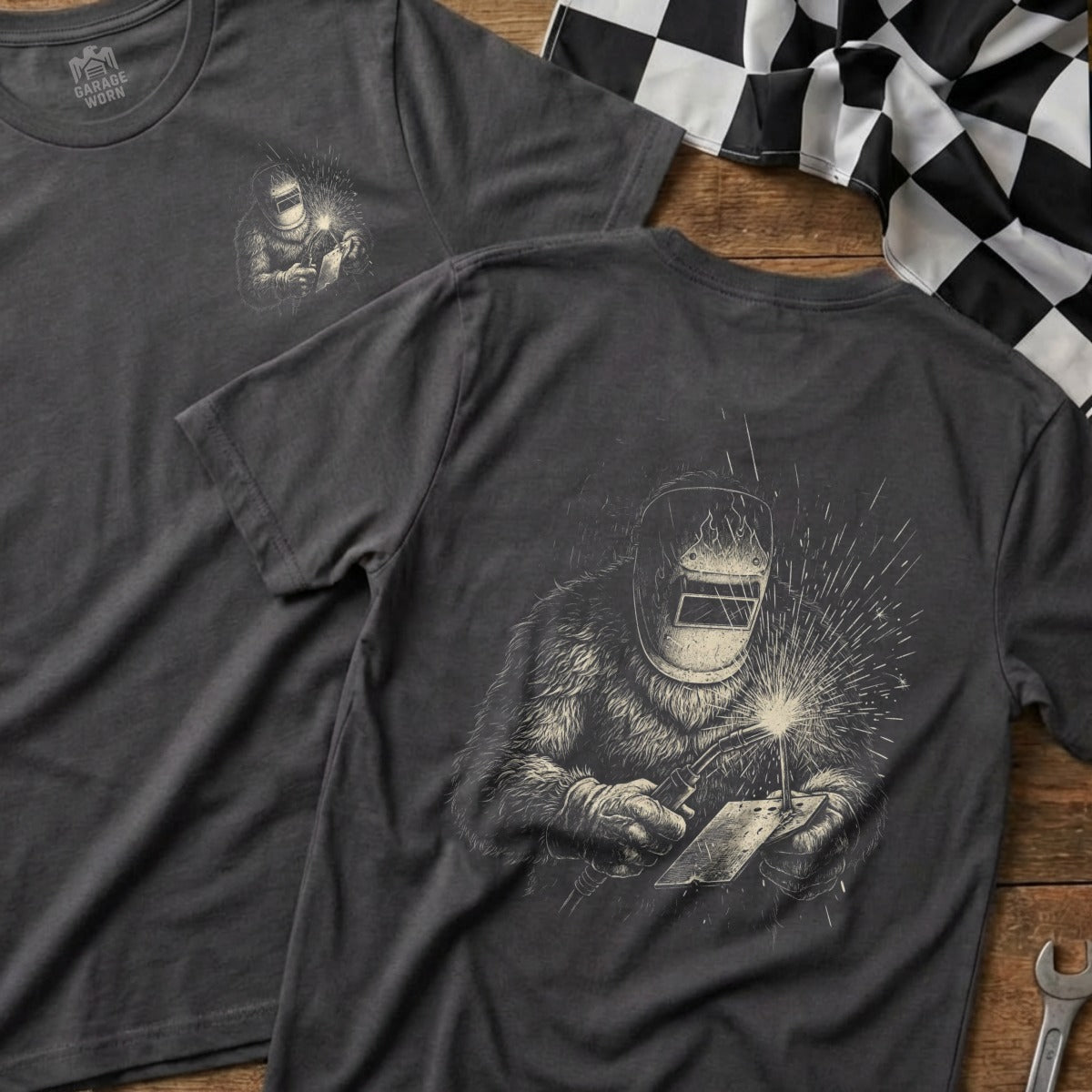 Dark t-shirt with a welder graphic on the back, front detail shows a checkered flag.