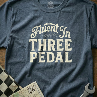 Blue t-shirt with "Fluent In Three Pedal" text and Route 66 map detail.