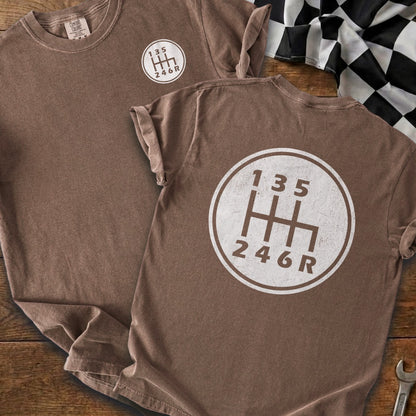 Brown t-shirt with a circular graphic of a manual transmission shift pattern.