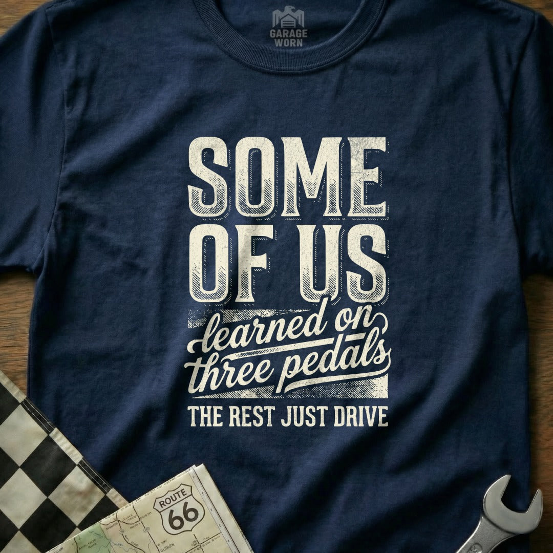 Navy t-shirt with "SOME OF US learned on three pedals THE REST JUST DRIVE" text.