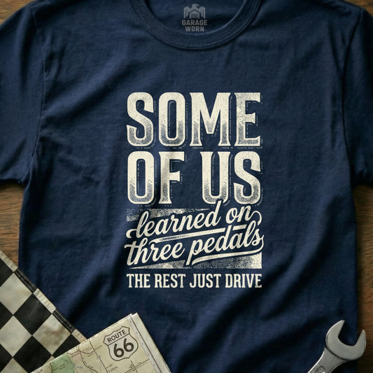 Navy t-shirt with "SOME OF US learned on three pedals THE REST JUST DRIVE" text.