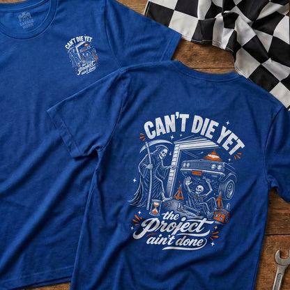 Blue t-shirt with Grim Reaper, skeleton, and car graphic with text "Can't Die Yet The Project Ain't Done".
